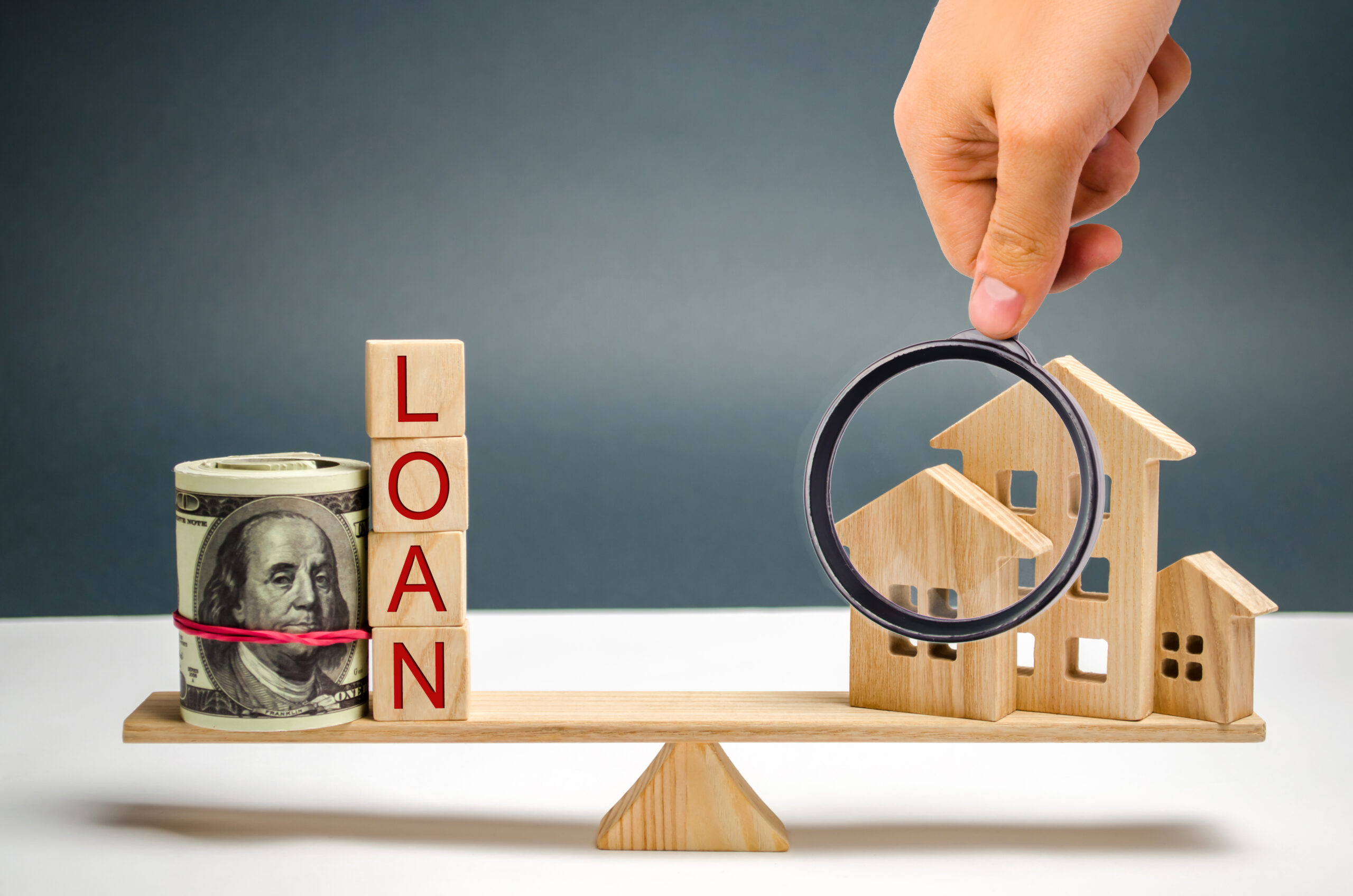 Miniature wooden house, dollars and the inscription Loan on the scales. Buying a home in debt. Family investment in real estate and risk management concept. Loan for a mortgage. apartment rental sale