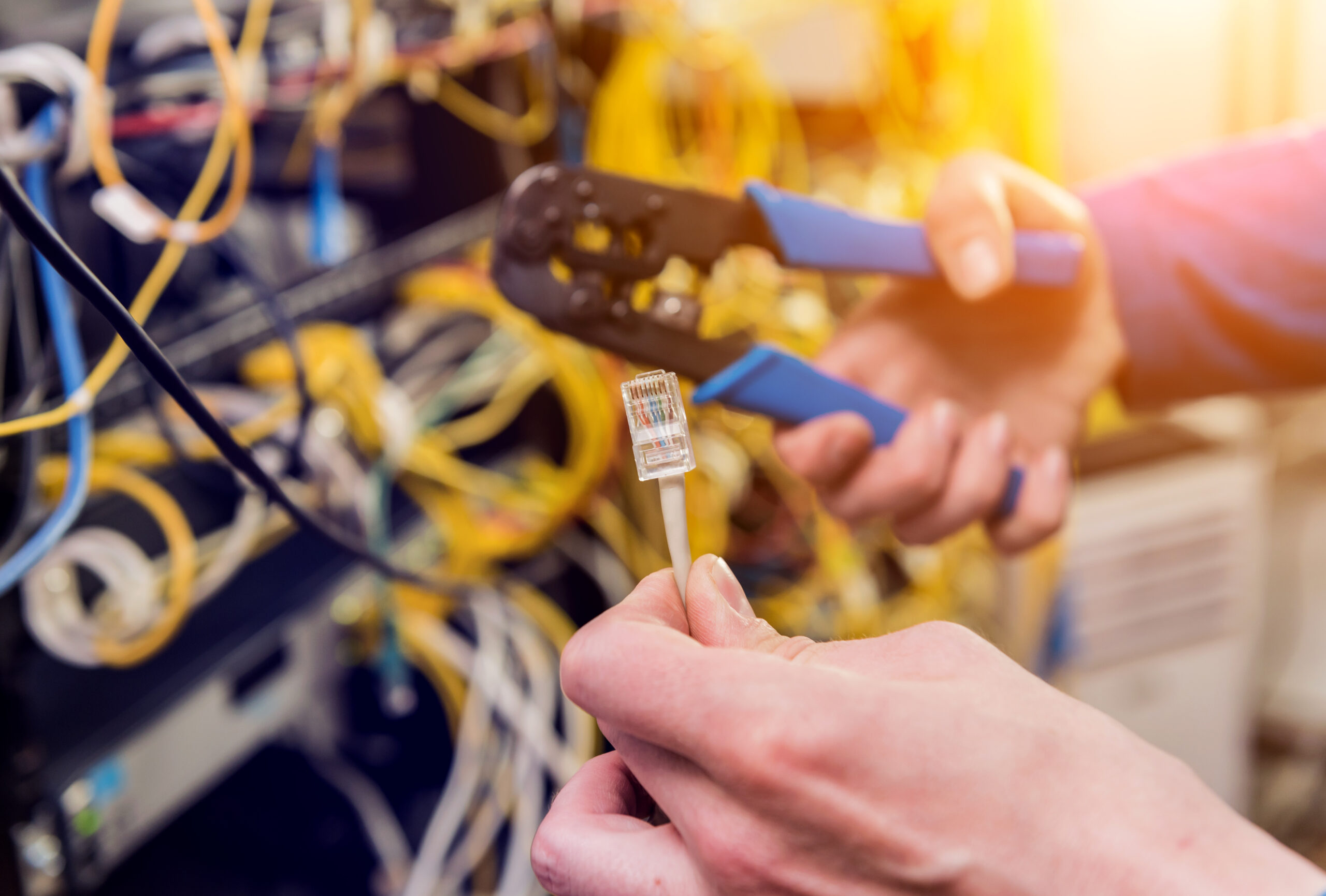 Network engineer working in server room. Connecting network cables to switches. Data center